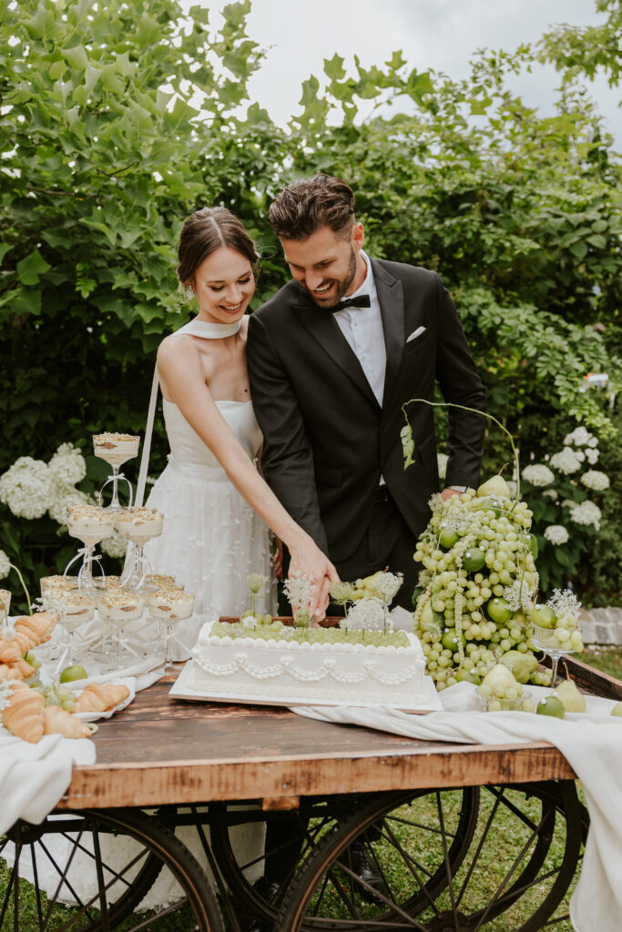 Exklusive Hochzeiten in Bayern – Warum Ästhetik hier eine Herausforderung ist 10 Brautpaar beim Kuchen anschneiden bei einer exklusiven Hochzeit in Bayern.